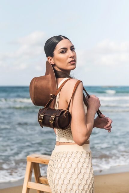 model holding Handcrafted leather buckle barrel bag with structured tube shape by Jirakis Leather
