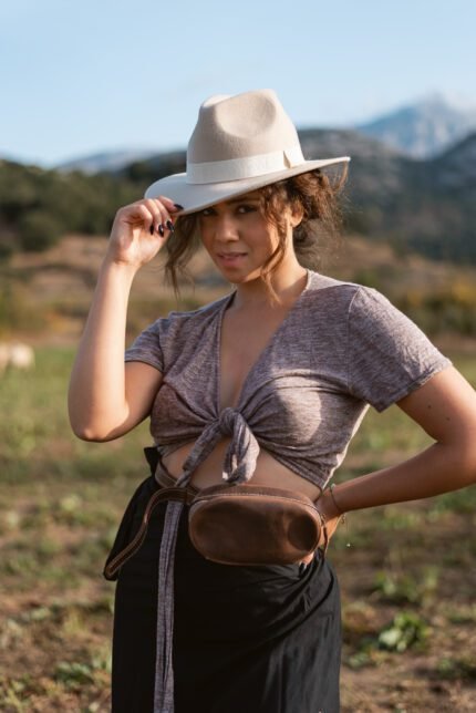 Woman wearing genuine leather belt bag around waist in outdoor field, handcrafted by Jirakis Handcrafted Leather in Crete.