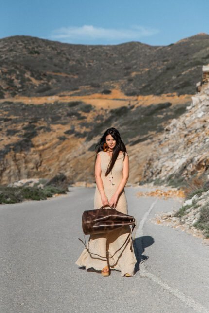 model holding a Leather travel duffle bag with single shoulder strap handcrafted in Crete by Jirakis Handcrafted Leather